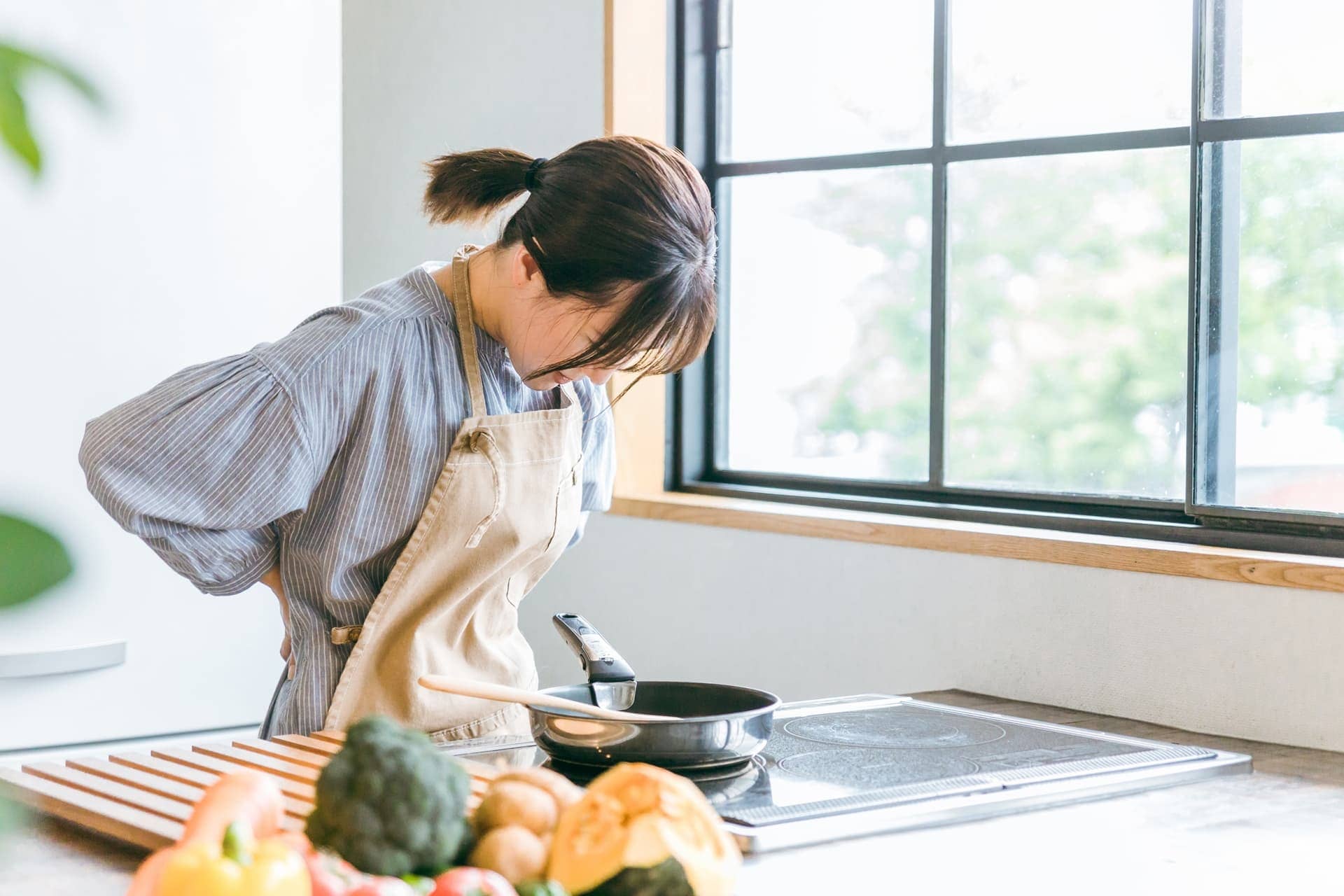 腰痛改善が必要な女性が料理を作っている