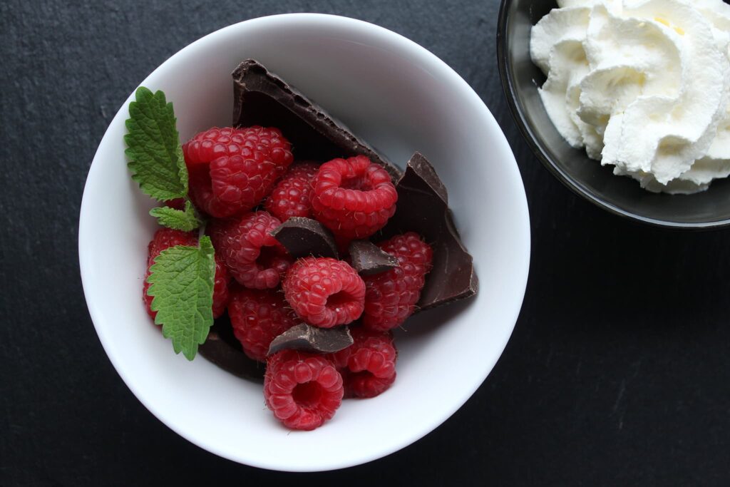 top view of raspberries chocolate and mint in white dish 1